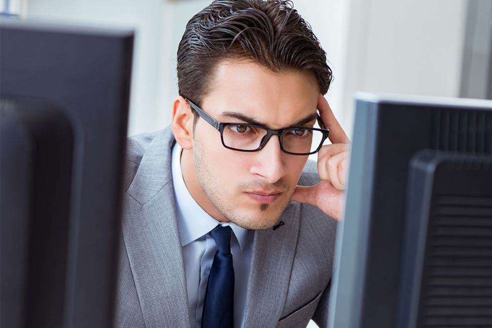 Foto: Person grübelt vor Bildschirmen